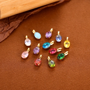 Colorful zircon drop pendants in gold stainless steel finish displayed on brown fabric