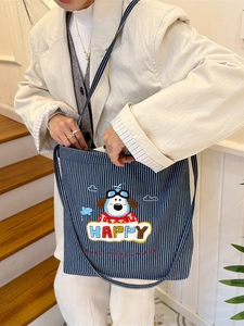 Blue striped canvas tote bag with embroidered cartoon puppy and happy text on a model