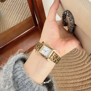 Detail of H-shaped gold watch with leopard print strap and rhinestone dial markers
