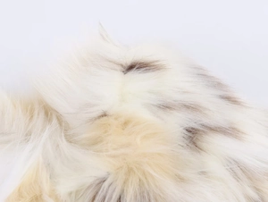 Close-up macro view of soft white faux fur texture with natural brown spots on the coat