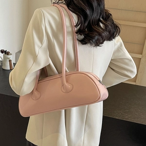 Pink high-shine faux leather baguette shoulder bag with slim straps worn by a model
