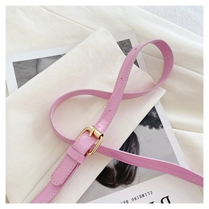 Detail of pink patent leather belt with a polished gold metal square buckle