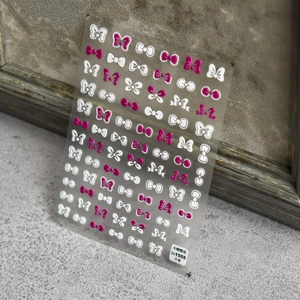 3D embossed nail stickers with pink and white bow patterns on a grey matte background