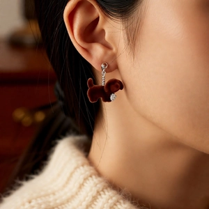 Close-up of brown flocked dog earrings with heart-shaped zircon drop on model ear