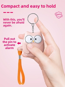 Pink owl personal alarm keychain shown in hand with pull-pin activation detail