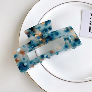 Large acrylic hair claw clip with colorful terrazzo pattern on a white plate