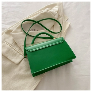 Détail du sac à main vert tilleul en simili cuir avec accents dorés sur blazer beige
