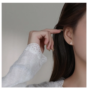 Close-up detail of silver crescent moon stud earring with sparkling zircons on model ear
