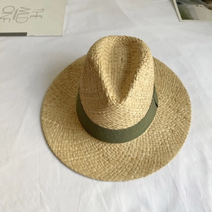 Close-up of woven straw hat texture with an olive green ribbon band decoration