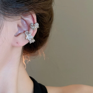Close-up of silver heart and star ear cuffs with cubic zirconia on female model's ear