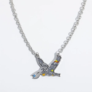 Detailed view of vintage flying bird pendant with colorful enamel and blue gemstone inlay