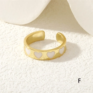 Detailed close-up of adjustable gold ring featuring white enamel hearts on surface