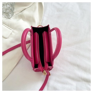 Vue de dessus d'un sac à main magenta en similicuir avec fermeture éclair sur un blazer blanc