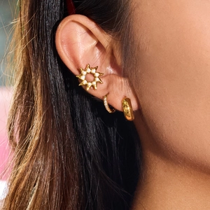 Gros plan détaillé du ear cuff soleil en or 18 carats et parure de boucles d'oreilles