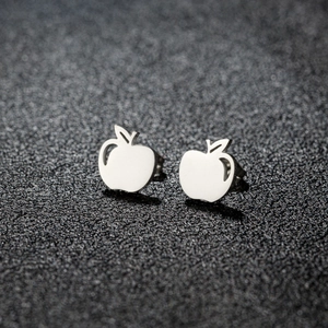 Close-up of polished silver apple-shaped stainless steel stud earrings on black surface