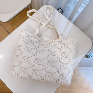 Detail of white quilted tote bag featuring red rabbit embroidery and dual shoulder straps