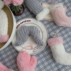 Détail d'ornements de Noël en peluche avec gants et chaussettes roses et gris sur une assiette
