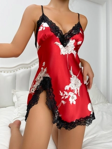 Detail of red silk sleepwear with white floral prints and black lace trim on the hem