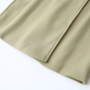 Detailed close-up of wool blend fabric texture and stitching in sage green coat