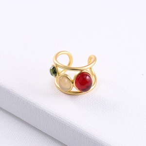 Macro detail of gold adjustable ring set with green, beige and red cabochon stones
