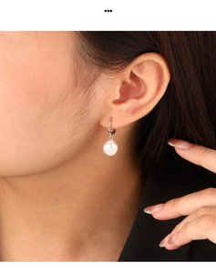 Close-up of a white baroque freshwater pearl earring on model with silver hoop