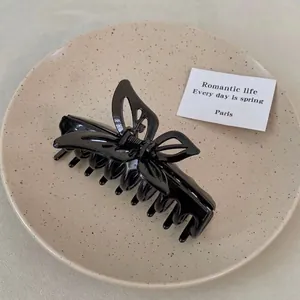 Close-up of glossy black butterfly hair claw clip with multi-tooth design on a plate
