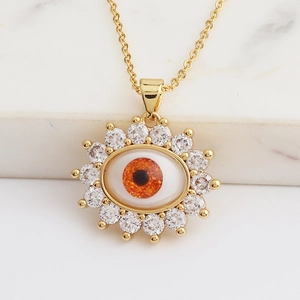 Macro shot of gold evil eye pendant featuring orange center stone and zircon stones