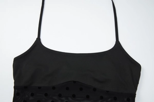 Détail d'un caraco noir montrant le tissu lisse cousu avec du tulle transparent à pois