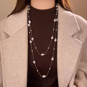 Detailed view of layered baroque pearl necklace styled over a cozy turtleneck and wool coat