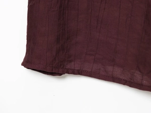 Detailed macro view of deep burgundy wrinkled texture fabric with precise hem stitching