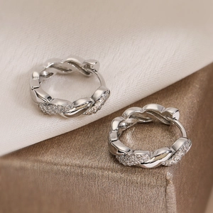 Boucles d'oreilles créoles torsadées en argent avec zircons sur tissu en soie blanc