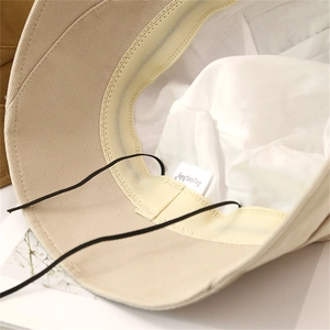 Detail of breathable mesh sweatband and adjustable black drawstring inside beige sun hat