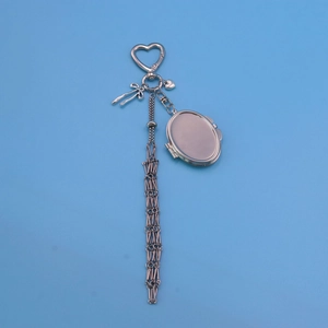 Silver metal heart keychain with bow, locket, and chain tassel on a blue background