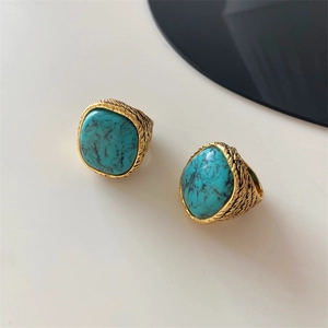 Detailed top view of gold textured rings featuring large turquoise stones with black veins