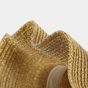 Macro detail of golden woven straw hat showing shimmering metallic threads and texture