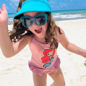 Close-up of children's pink metallic swimsuit with mermaid print and ruffle detail