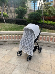 Close-up of baby stroller sunshade with white lace embroidery and bee pattern detail