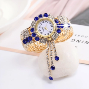 Detailed close-up of gold quartz watch with blue rhinestones and fringe charm detail