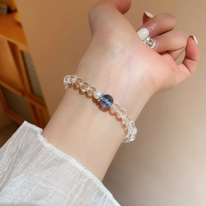 Gros plan d'un bracelet en perles de cristal blanc et perle avec une perle bleue au poignet