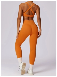 Detail of high-waisted orange yoga leggings and cross-back sports bra for fitness