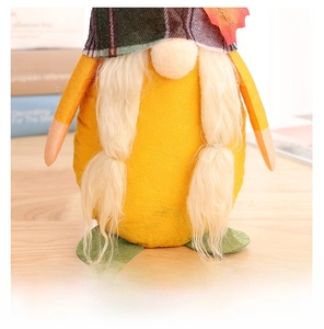 Close-up of autumn gnome with maple leaf detail and plaid hat on wooden background