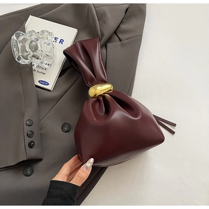 Detail of burgundy cloud bag featuring pleated leather texture and a large gold metal buckle
