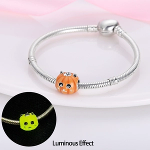 Silver snake chain bracelet featuring a glowing orange pumpkin charm with luminous effect