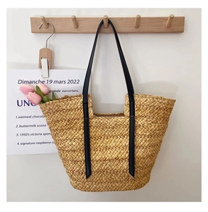 Détail du sac cabas en paille tressée avec anses en cuir noir et intérieur spacieux
