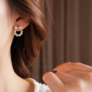 Gros plan d'une boucle d'oreille nœud en perles et zircons portée avec élégance