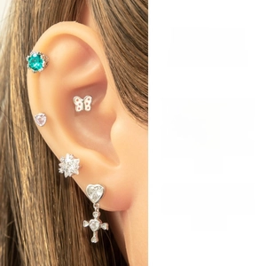 Detail showing assorted titanium steel butterfly studs and heart cross earrings on ear