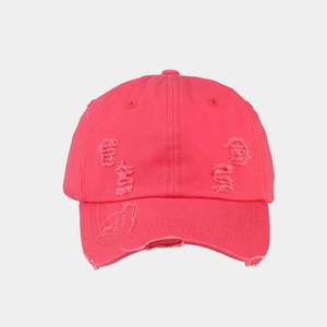 Detail of red washed cotton baseball cap featuring vintage distressed torn hole effects