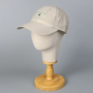 Quick-dry beige baseball cap with green clover embroidery on a mannequin head