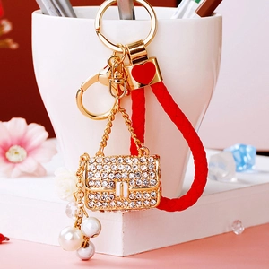Detail of a sparkling crystal mini bag keychain with red braided rope and pearl charms