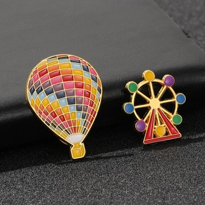 Detail of colorful enamel hot air balloon and Ferris wheel brooches on black leather